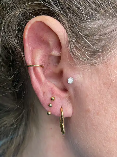 Composición de piercings en oreja destacando un tragus con brillante clásico en Sarrià