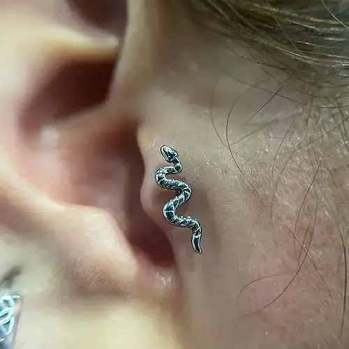 Perforación Tragus curada con joyería minimalista en Eterna Tattoo.