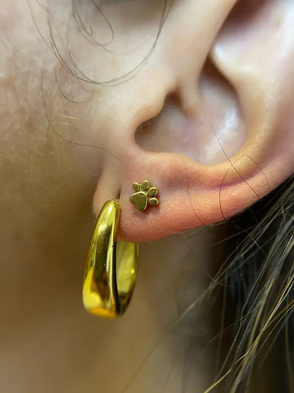 Piercing en el lóbulo con joya original en forma de huella de perro - Estudio Barcelona